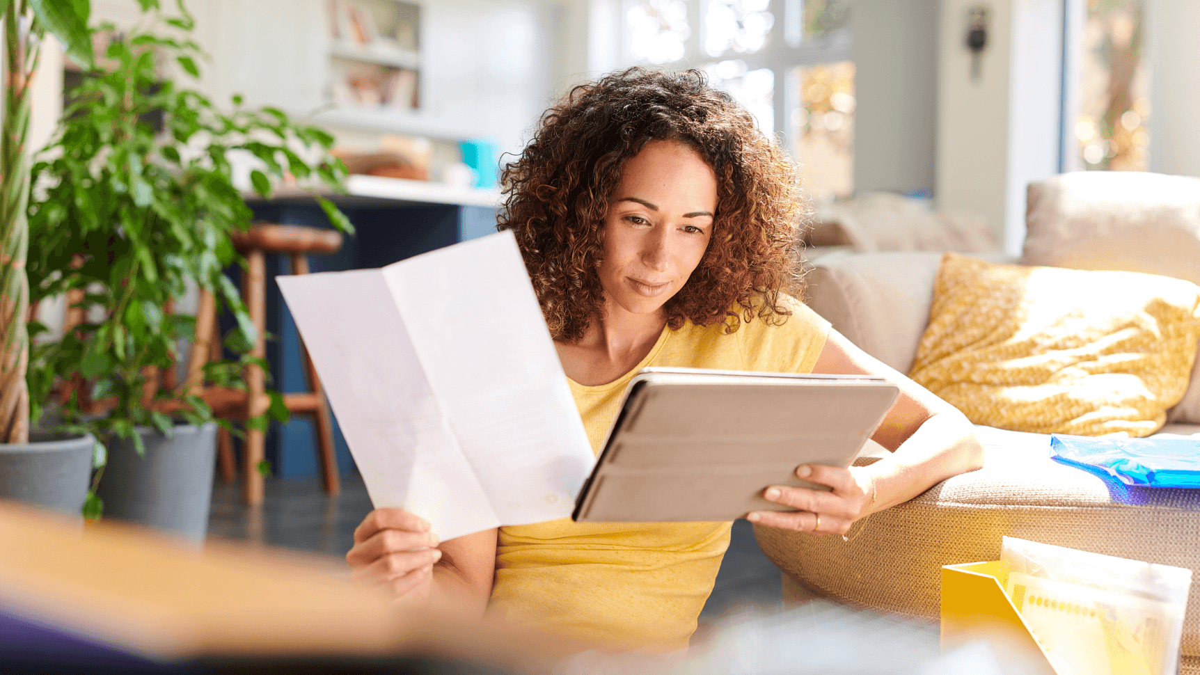 woman reading papers and tablet screen