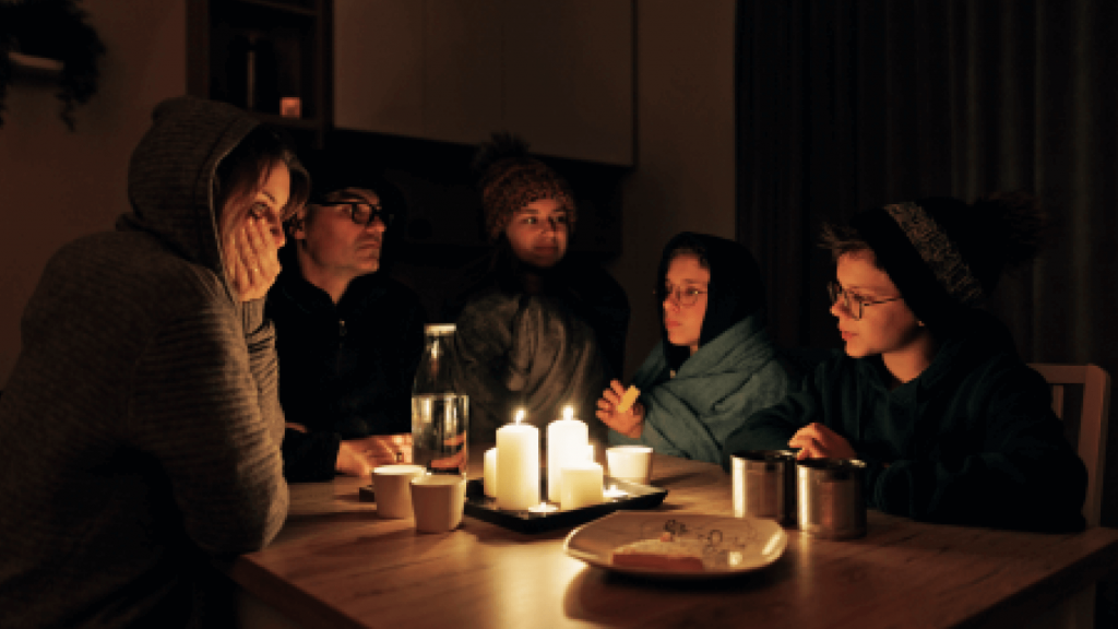 family sat in blankets around candles for warmth